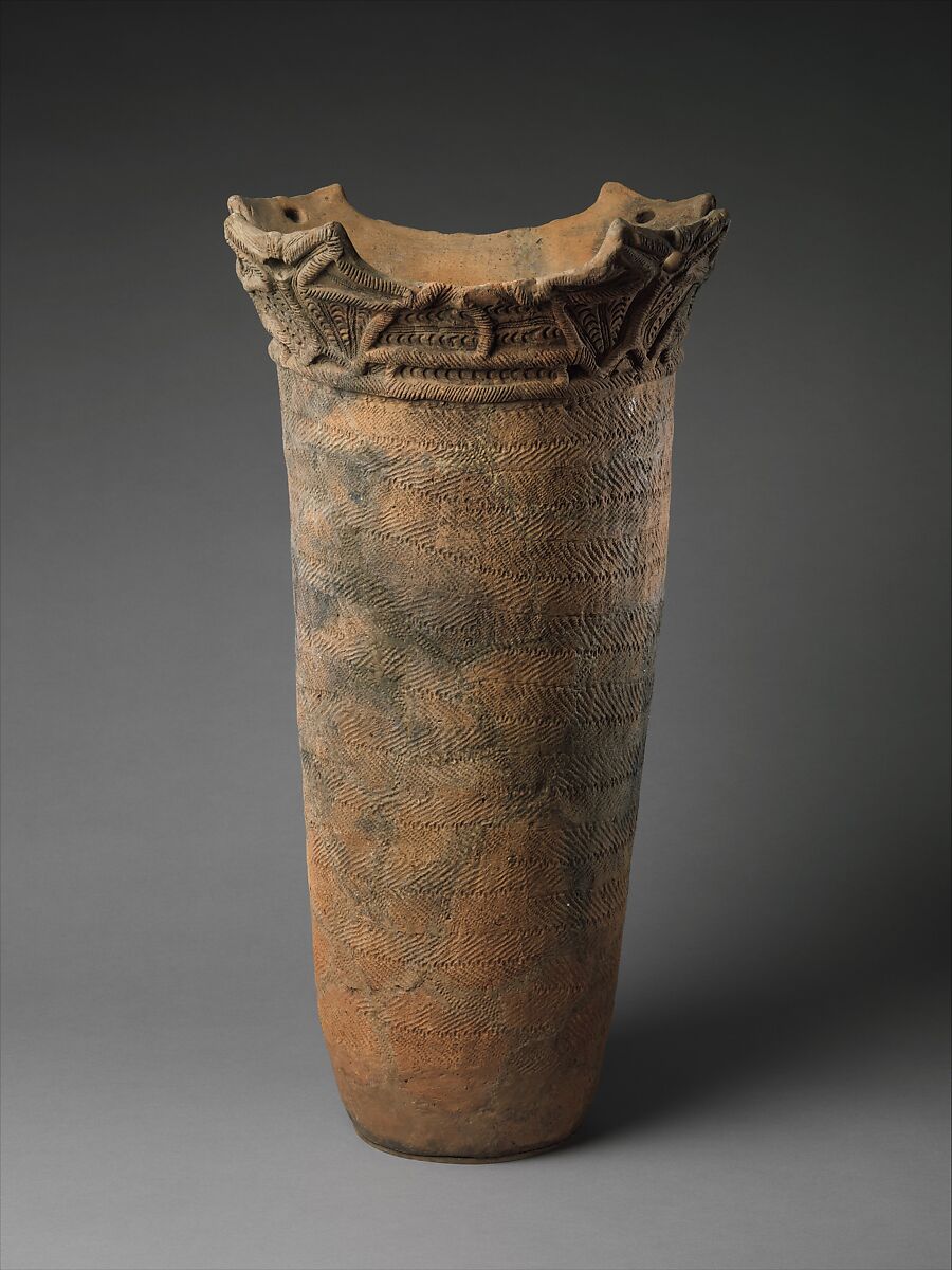 Tall Jōmon vessel with fine cord impressions across its body and a concentrated band of sculptural ornament around the rim.